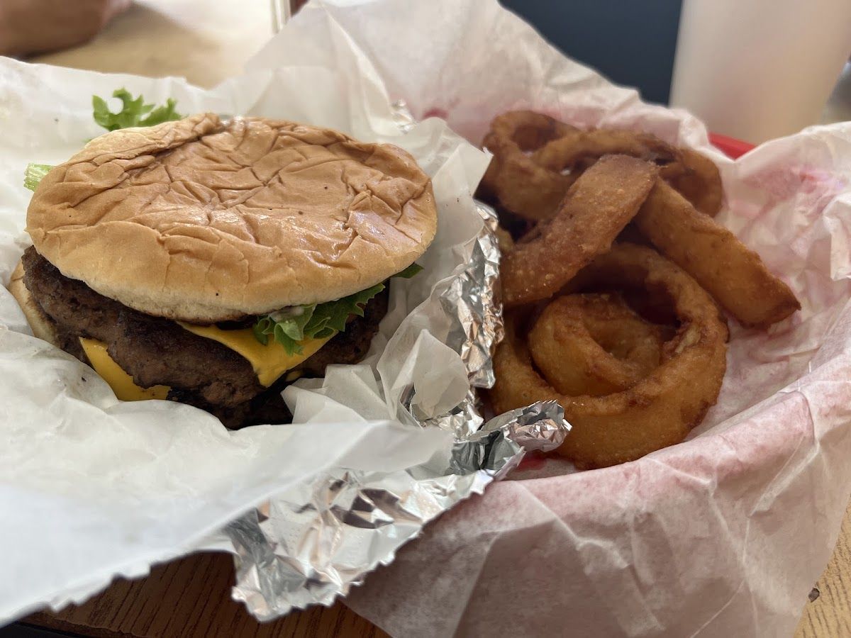 Cheeseburger in a paper-lined basket next to a pile of onion rings